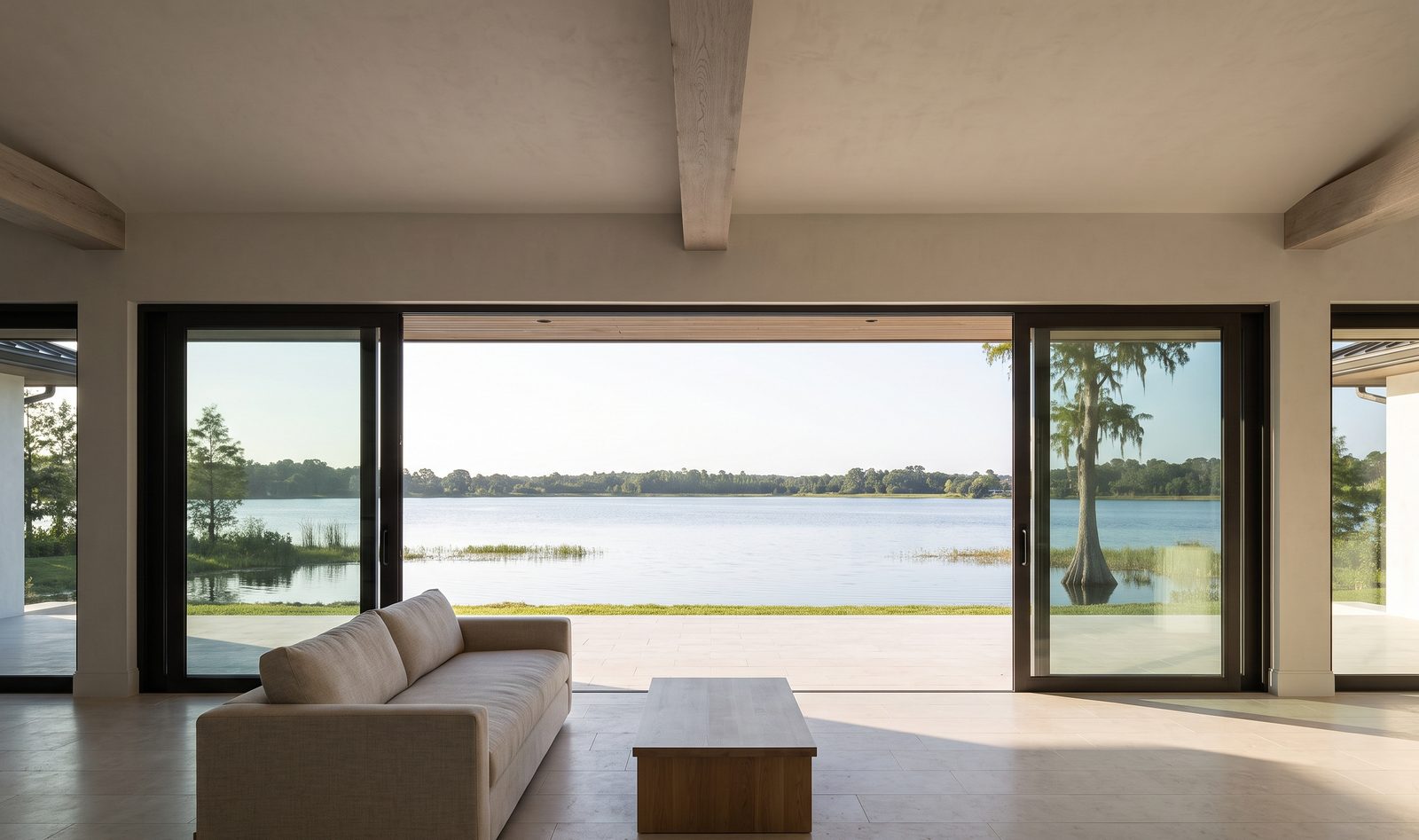 The great room looking out through the opened glass wall to the lake beyond