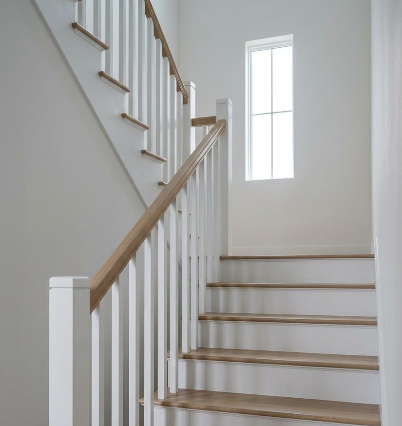 The stair with white painted risers and white oak treads, shadows falling across them from a window above
